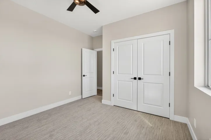 Room featuring neutral wall tones, patterned carpet flooring, white trim, and a multi-pane window