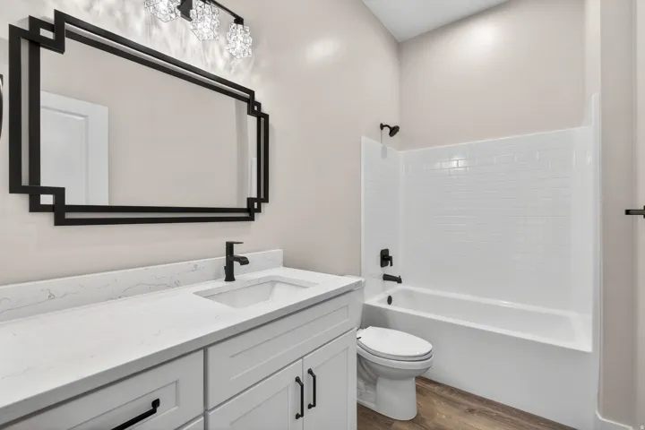Bathroom featuring a white vanity with a light-toned countertop, black fixtures, and a decorative mirror