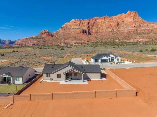 New construction residence featuring a stucco exterior, dark shingle roof, and an expansive paved patio