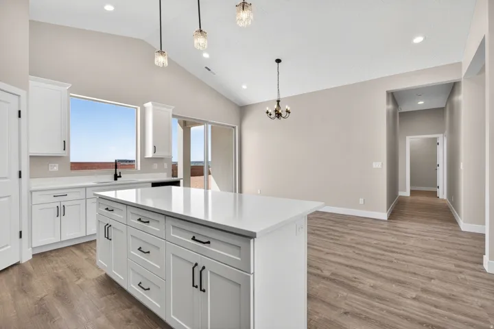 Open-concept kitchen and dining area featuring a vaulted ceiling and wood-finish flooring