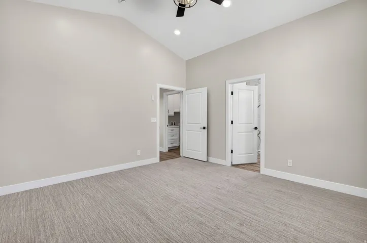 Spacious room featuring vaulted ceilings, light-colored walls, and patterned carpeting