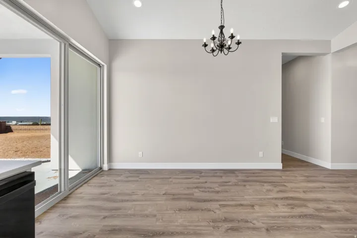 Spacious room featuring wood-finish flooring, light grey wall tones, and a black wrought iron chandelier