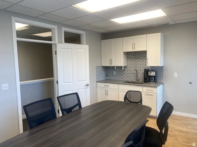 Full kitchenette featuring white shaker-style cabinetry, a subway tile backsplash, and a stainless steel sink
