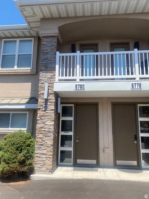 Exterior featuring stone veneer accents, stucco siding, and white window frames