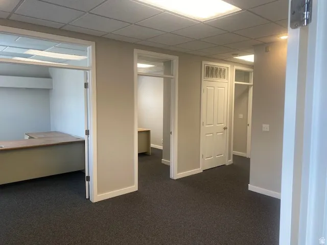 Carpeted interior office space with multiple private rooms featuring drop ceilings with integrated lighting