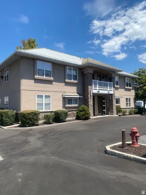 Two-story commercial building featuring a metal roof, stucco facade, stone accents, and an upper-level balcony with white railings