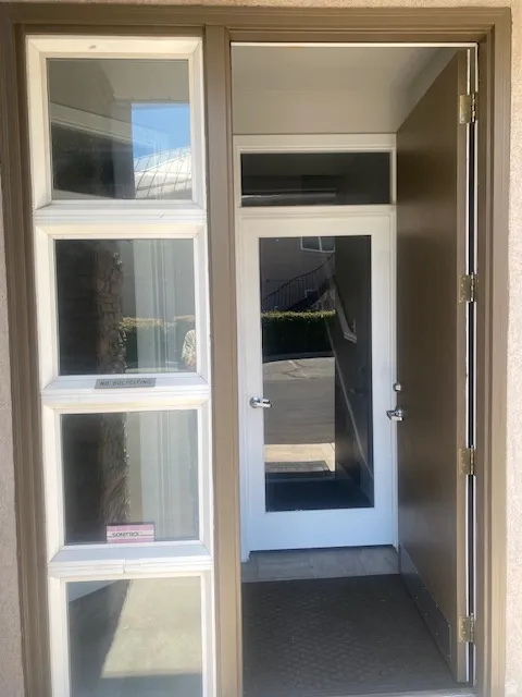 Entryway featuring a solid wood door, sidelight windows with white trim, and a glass-paneled interior door