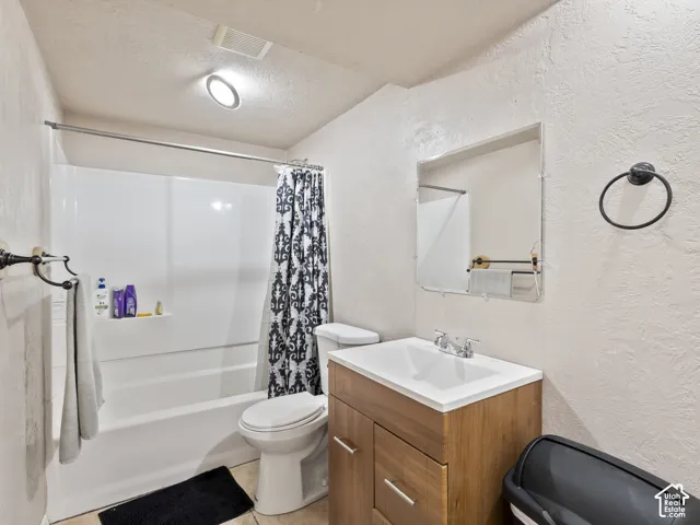 Full bathroom featuring a single vanity with wood-finish cabinetry, a white countertop, and a rectangular undermount sink with a chrome faucet
