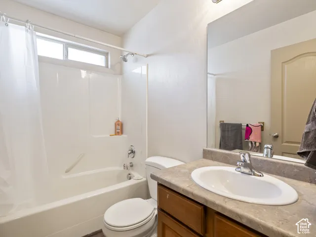 Bathroom featuring a combined tub and shower unit, a vanity with a light-toned countertop, and an oval undermount sink