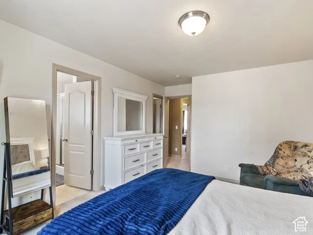 Room with carpeted flooring and white walls, featuring a white paneled door leading to a bathroom with a shower enclosure