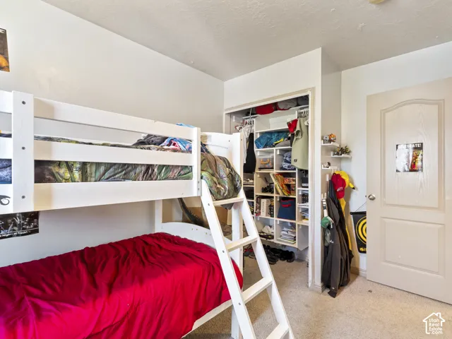 Bedroom featuring light-toned carpeting, white painted walls, and a white interior door with a silver-toned knob