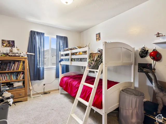 Bright room featuring a prominent window, white painted walls, wood-finish baseboards, and carpeted flooring