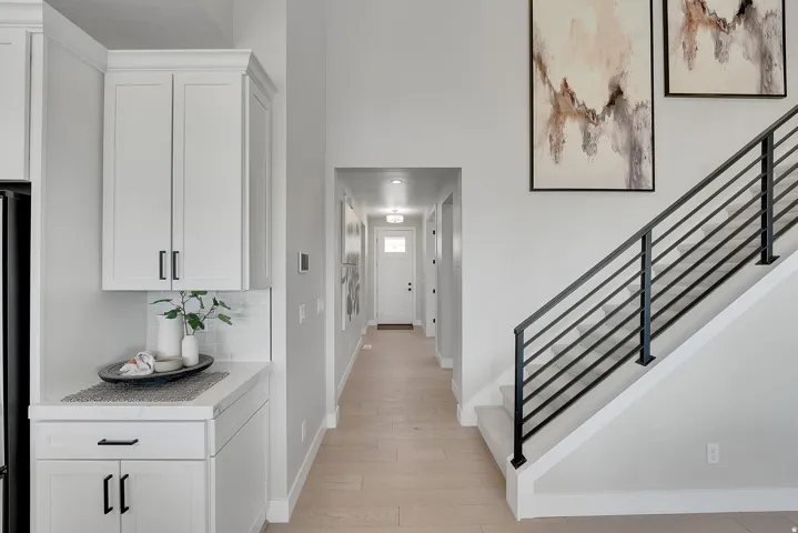 Entryway featuring light wood-finish flooring, a modern black metal staircase railing, and a white paneled door