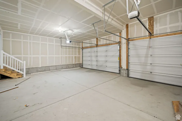 Two-car garage featuring a concrete floor, two white garage doors, and unfinished drywall walls