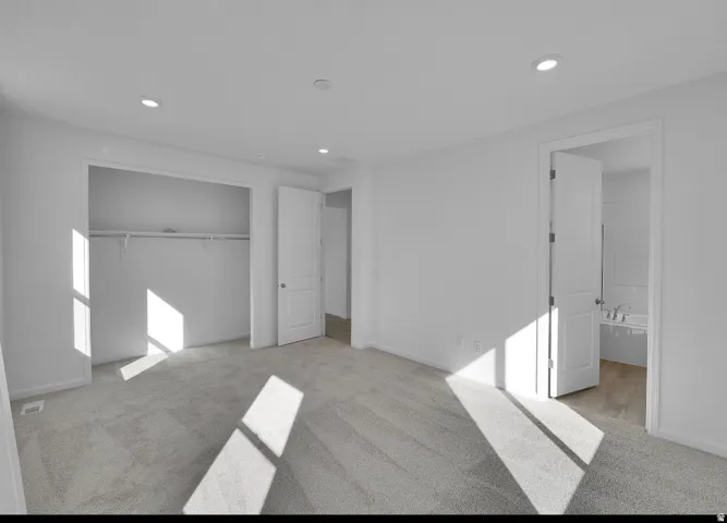 Spacious room featuring light gray carpet, recessed lighting, and a white interior color palette