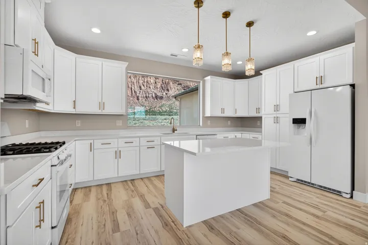 Spacious kitchen featuring white cabinetry, light-toned countertops, and wood-finish flooring