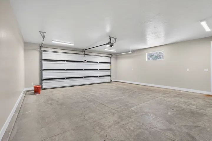 Spacious garage featuring a sectional overhead door, concrete flooring, ample overhead lighting, and a frosted transom window