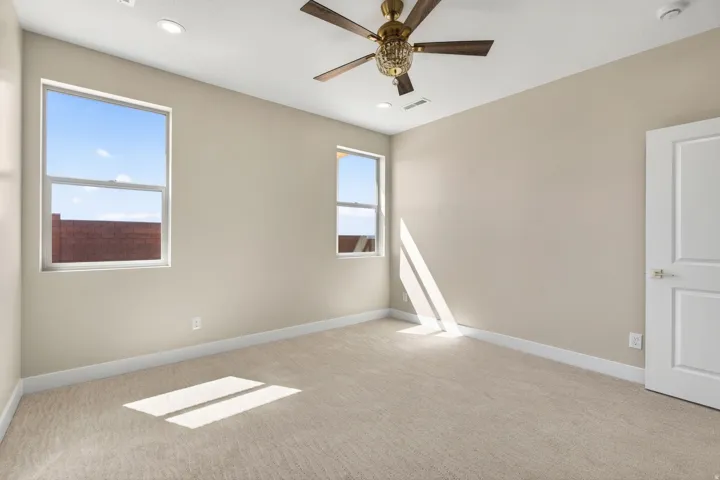 Carpeted room featuring two windows, recessed lighting, and a ceiling fan with an ornate light fixture