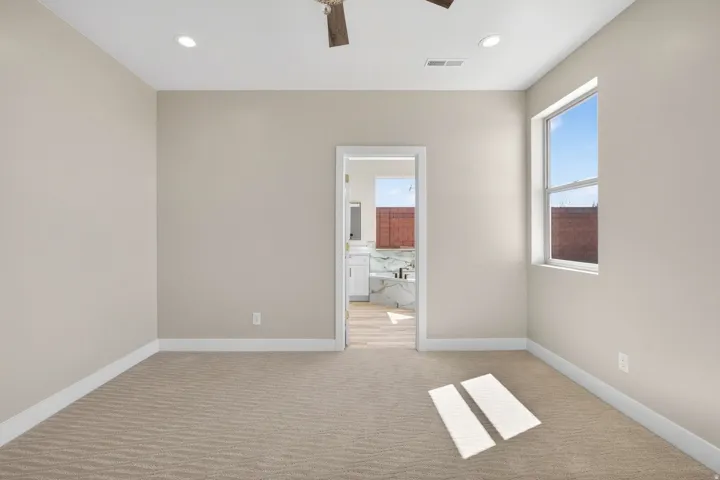 Neutral-toned room with patterned carpeting, recessed lighting, and a ceiling fan