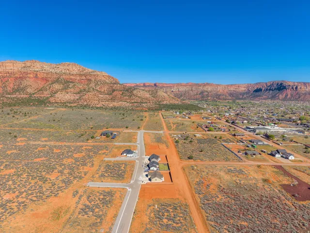 Expansive desert landscape featuring graded roads and building pads, bordered by distant mountainous terrain