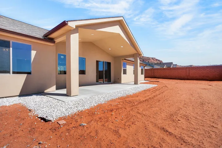 Expansive backyard with a covered patio, concrete slab, and gravel perimeter
