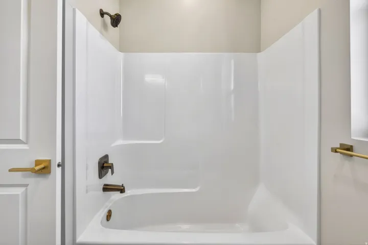 White acrylic tub and shower combination with bronze fixtures