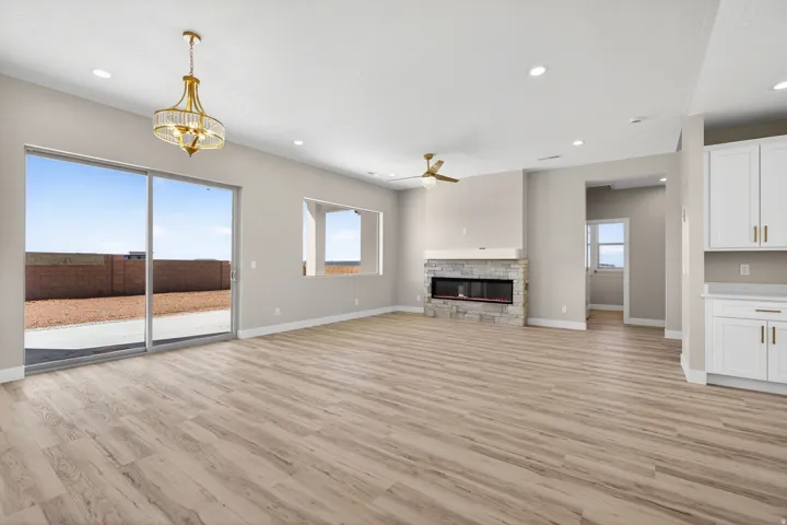 Spacious living area featuring wood-finish flooring, a stone-clad fireplace with a mantel, and a ceiling fan