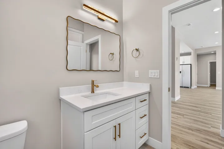 Bathroom vanity featuring a white cabinet, integrated sink, gold-tone faucet, and gold-tone hardware