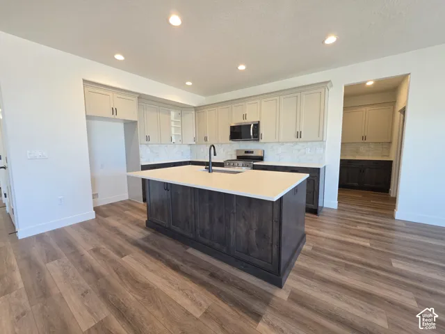 Gourmet kitchen featuring a substantial island with dark wood-finish cabinetry and a light-toned countertop, complemented by light-toned upper cabinetry