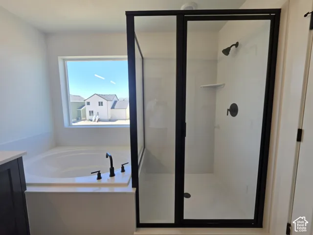 Spacious bathroom featuring a built-in soaking tub with matte black fixtures, a separate walk-in shower with clear glass enclosure and matte black frame, and a window providing natural light
