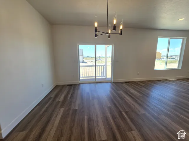 Spacious room featuring wood-finish flooring and a contemporary chandelier