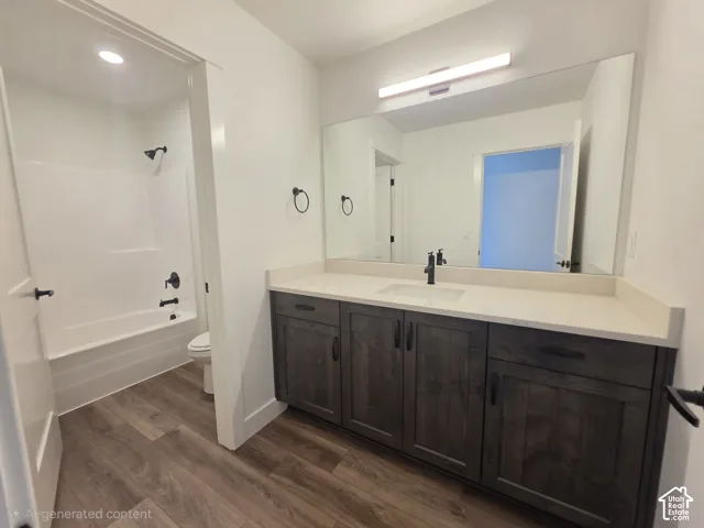 Bathroom featuring a wood-finish floor, a white tub with matte black fixtures, a white vanity countertop, and dark wood cabinetry