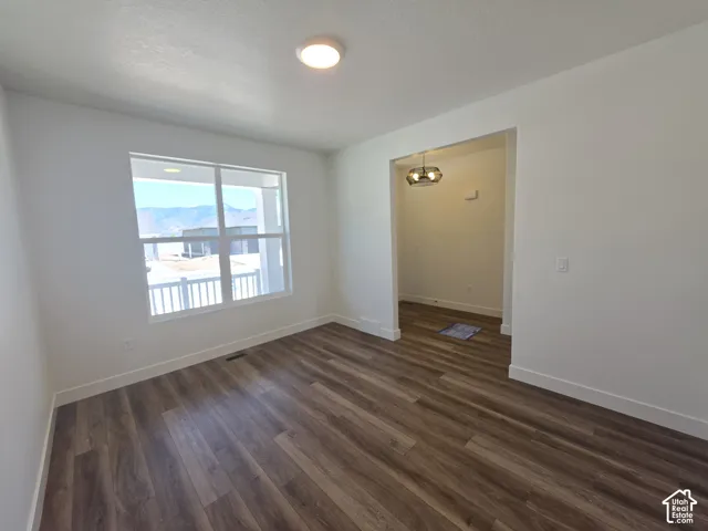 Spacious room featuring wood-finish flooring, white baseboards, and a large window offering mountain scenery