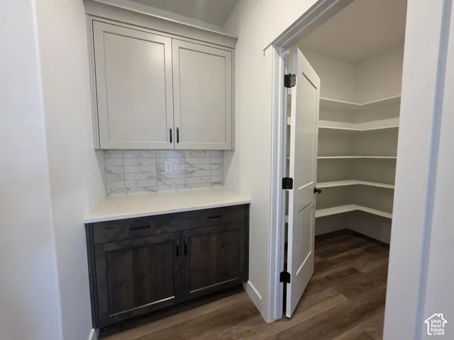 Built-in cabinetry with light-toned upper cabinets and dark wood-finish lower cabinets, featuring a light countertop and a subway tile backsplash