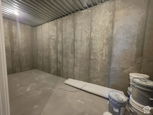 Unfinished basement space featuring concrete walls and flooring, and an exposed metal ceiling