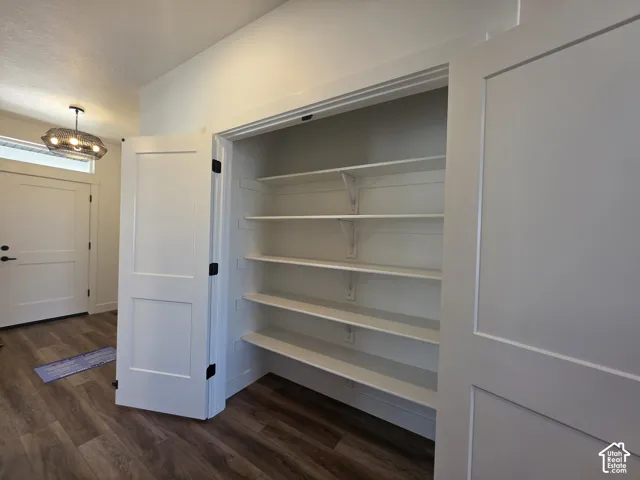 Built-in pantry with multiple white shelves, white shaker-style doors, and dark hardware