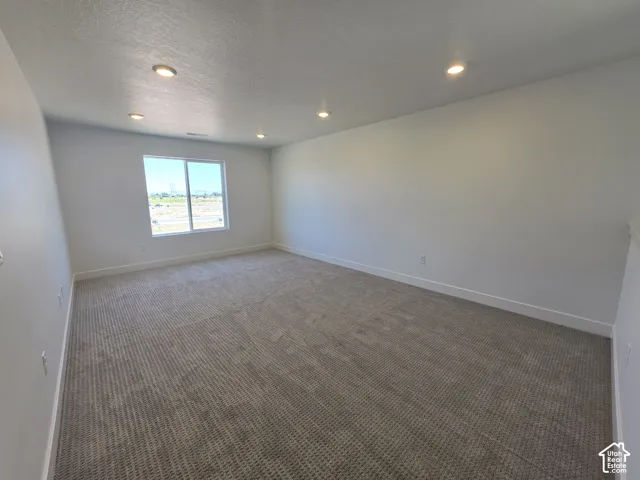 Spacious room featuring neutral carpeting and white painted walls