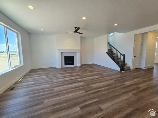 Spacious living area featuring wood-finish flooring, a contemporary fireplace with a decorative mantel, and recessed ceiling lighting