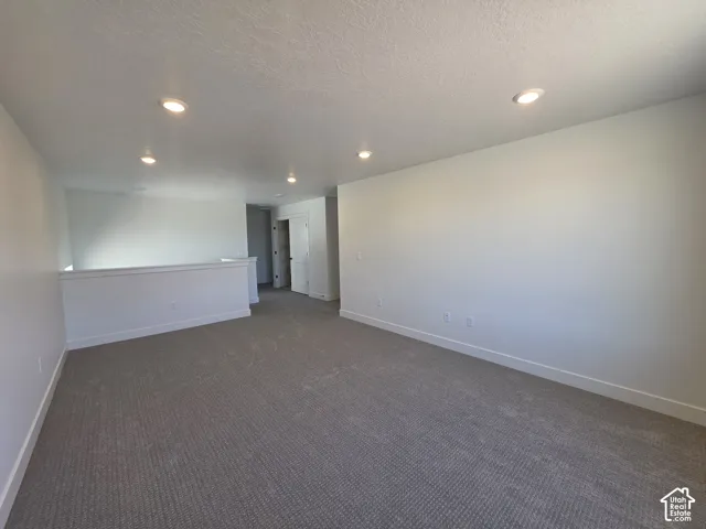 Spacious room featuring neutral carpeting, white walls, recessed lighting, and a white half-wall railing