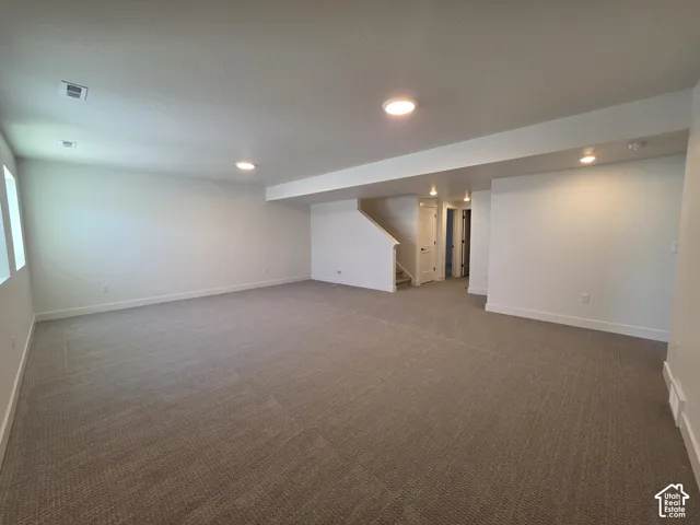 Spacious finished room featuring neutral carpeting, recessed lighting, and bright white walls