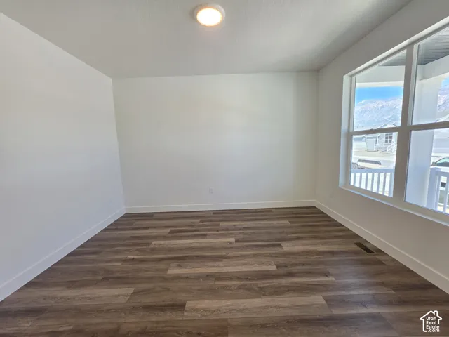 Room featuring wood-finish flooring, white baseboards, and a large window with white trim