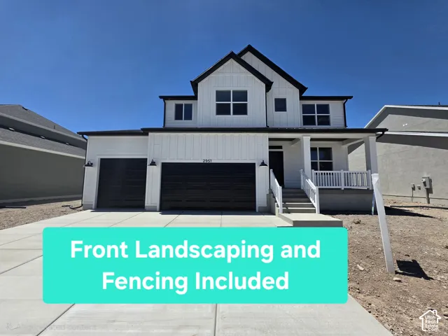 Two-story residence with a prominent gable roofline, white vertical and horizontal siding, an attached two-car garage with black doors, a covered front porch with white railings, and a concrete driveway