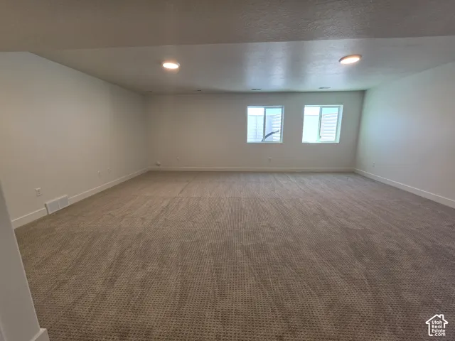 Spacious room featuring new carpeting, recessed lighting, white baseboards, and two windows