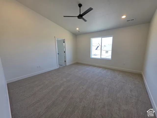 Spacious room featuring vaulted ceilings, neutral-toned carpeting, and a modern ceiling fan