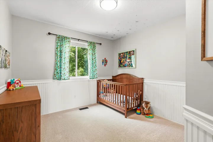 Light-filled room featuring a single window, overhead flush-mount lighting, wainscoting paneling, and carpet flooring