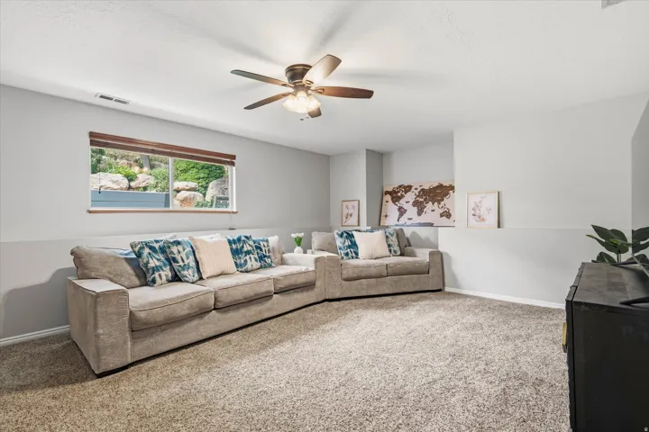 Spacious room featuring neutral paint, plush carpet flooring, and a ceiling fan with integrated lighting