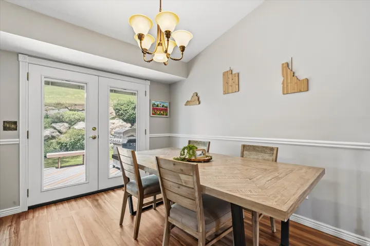 Vaulted ceiling dining area featuring wood-finish flooring and wainscoting
