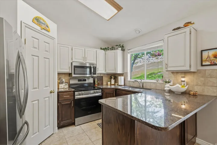 Kitchen featuring granite countertops, stainless steel appliances, a tile backsplash, and a breakfast bar