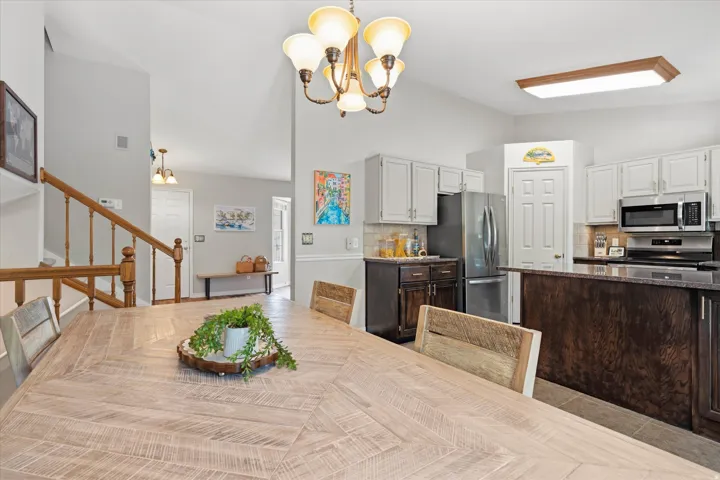 Open-concept kitchen and dining area featuring a vaulted ceiling and a wood-finish dining table