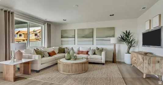 Bright living area featuring wood-finish flooring and recessed lighting. This home is To Be Built and the pictures are of a previous home.